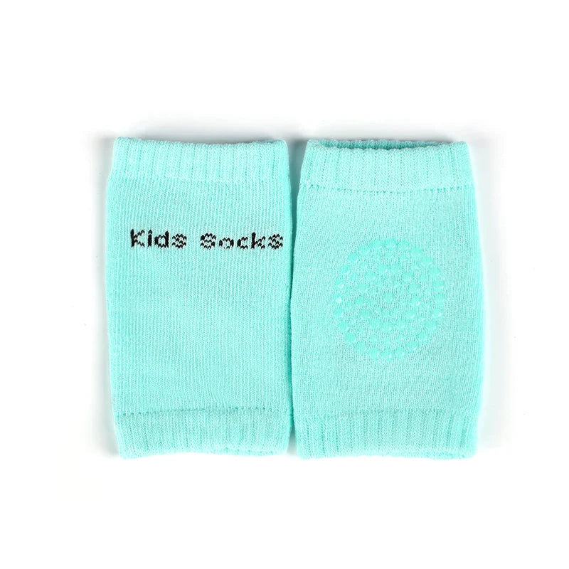 Non-slip baby knee pad in pink cotton with smiley face design, stacked with colorful pads for toddler protection during crawling.