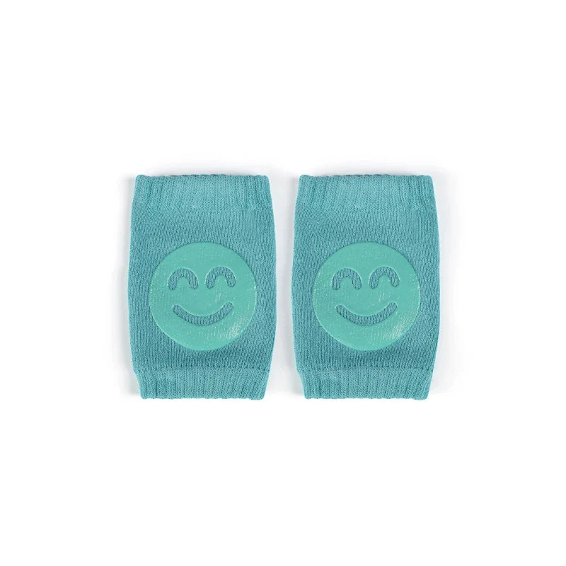 Non-slip baby knee pad in pink cotton with smiley face design, stacked with colorful pads for toddler protection during crawling.