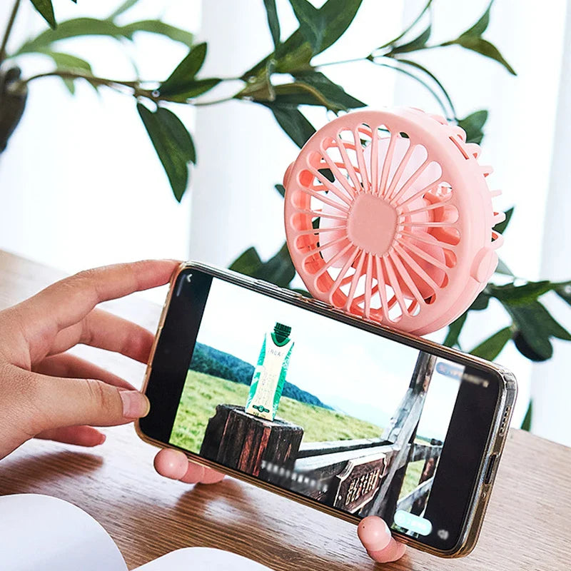 USB Rechargeable Handheld Electric Fan with flexible tripod legs and LED light, ideal for portable cooling on desks or travel use.