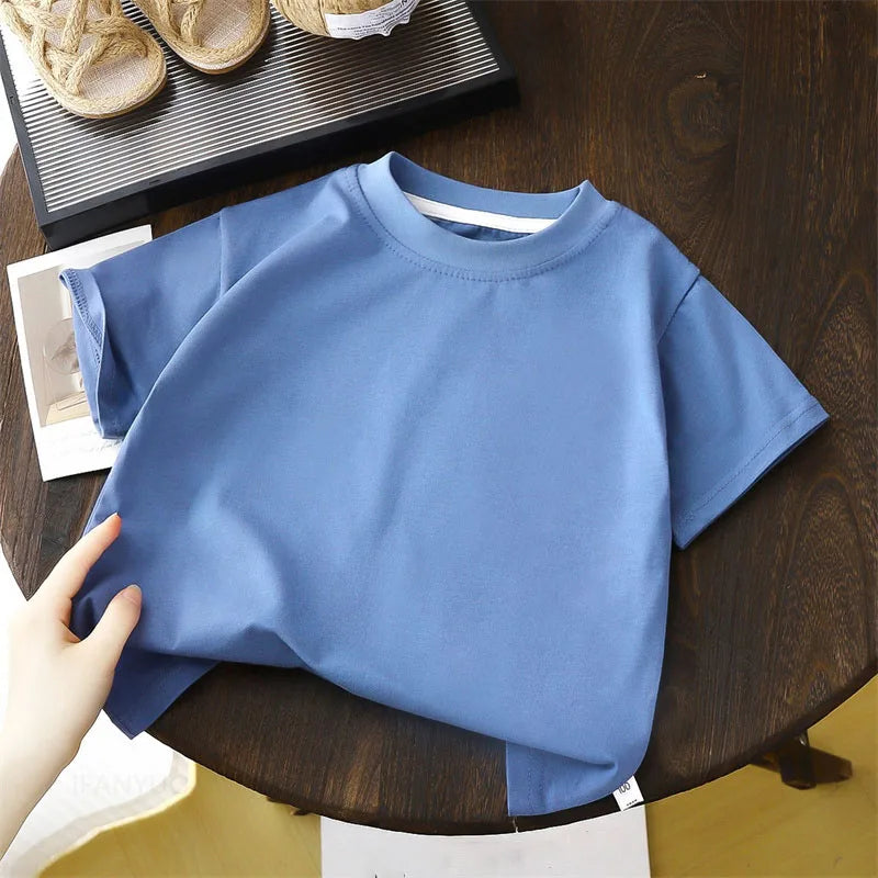 Solid cotton casual short sleeve T-shirts for kids in black, red, beige, and white colors, displayed on a wooden table.