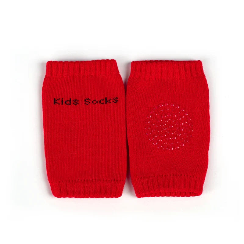Non-slip baby knee pad in pink cotton with smiley face design, stacked with colorful pads for toddler protection during crawling.