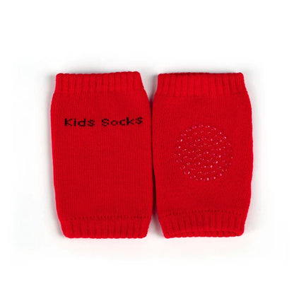 Non-slip baby knee pad in pink cotton with smiley face design, stacked with colorful pads for toddler protection during crawling.