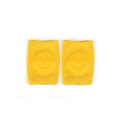 Non-slip baby knee pad in pink cotton with smiley face design, stacked with colorful pads for toddler protection during crawling.