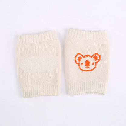 Non-slip baby knee pad in pink cotton with smiley face design, stacked with colorful pads for toddler protection during crawling.