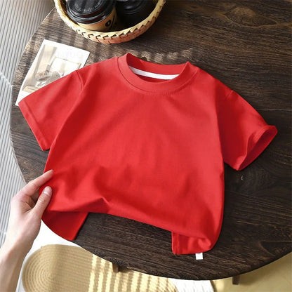Solid cotton casual short sleeve T-shirts for kids in black, red, beige, and white colors, displayed on a wooden table.