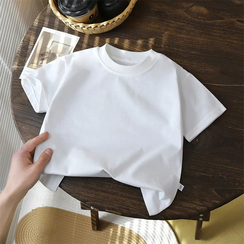 Solid cotton casual short sleeve T-shirts for kids in black, red, beige, and white colors, displayed on a wooden table.