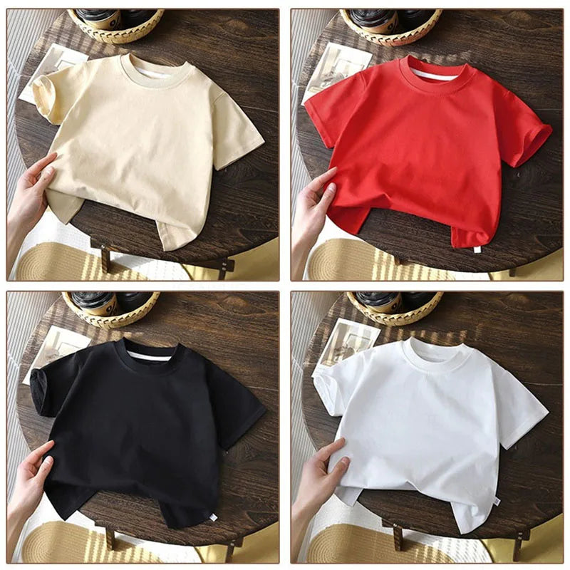 Solid cotton casual short sleeve T-shirts for kids in black, red, beige, and white colors, displayed on a wooden table.