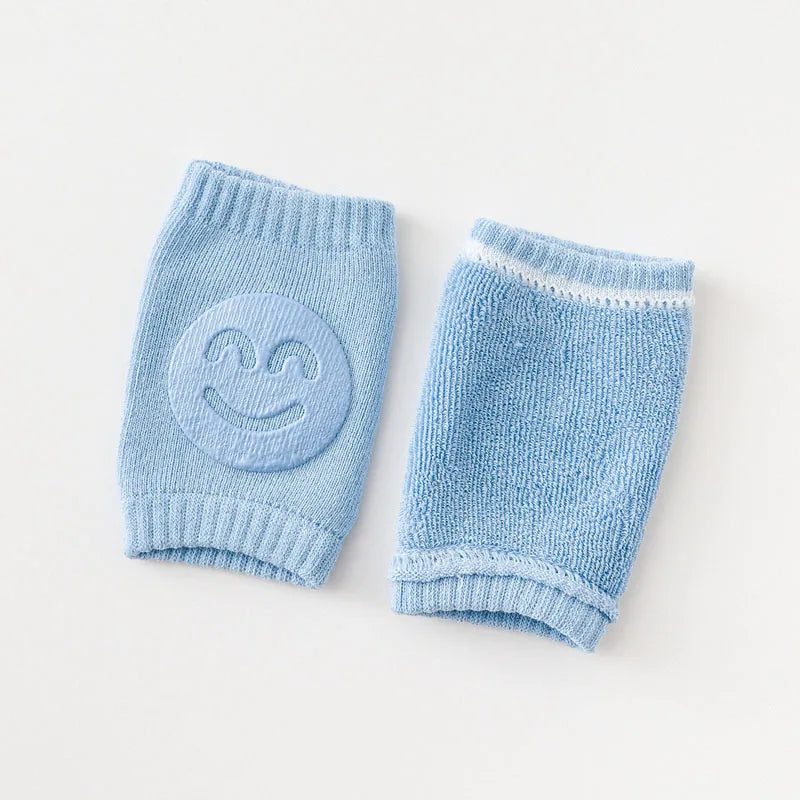 Non-slip baby knee pad in pink cotton with smiley face design, stacked with colorful pads for toddler protection during crawling.