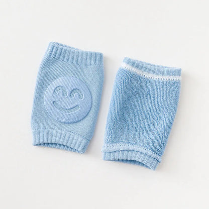 Non-slip baby knee pad in pink cotton with smiley face design, stacked with colorful pads for toddler protection during crawling.