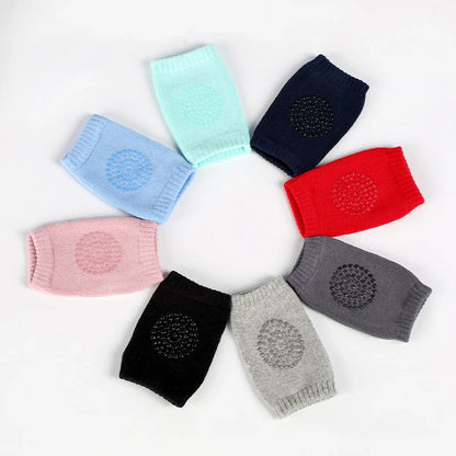 Non-slip baby knee pad in pink cotton with smiley face design, stacked with colorful pads for toddler protection during crawling.