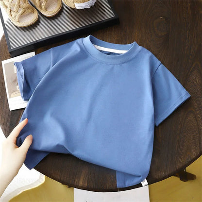 Solid cotton casual short sleeve T-shirts for kids in black, red, beige, and white colors, displayed on a wooden table.