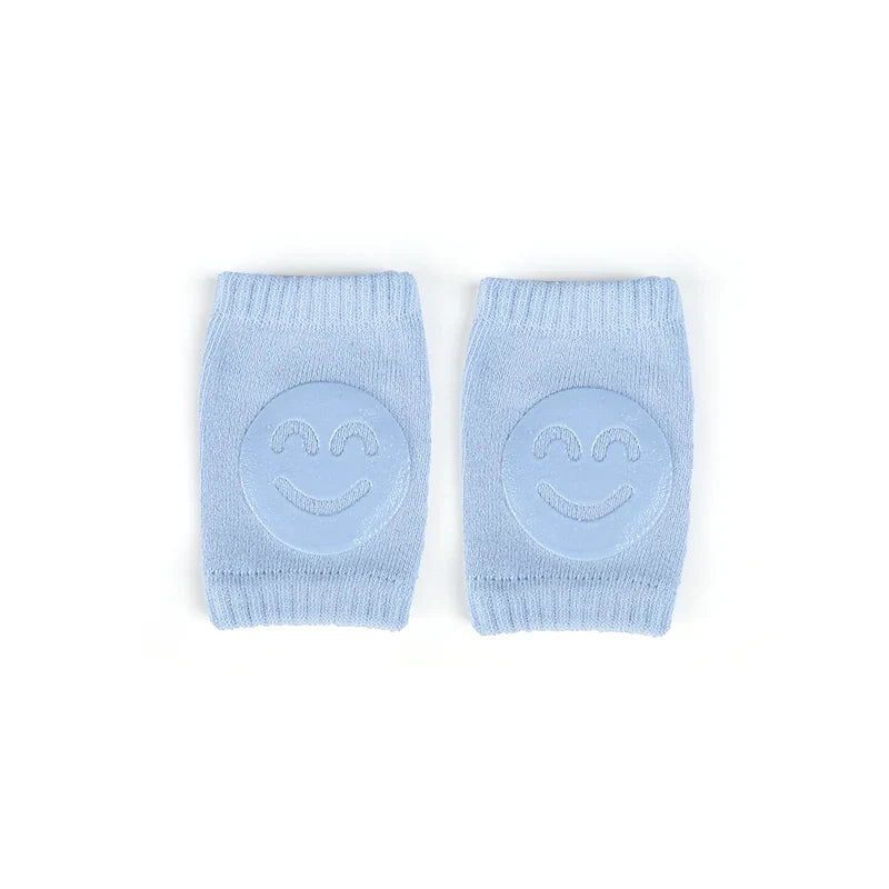 Non-slip baby knee pad in pink cotton with smiley face design, stacked with colorful pads for toddler protection during crawling.
