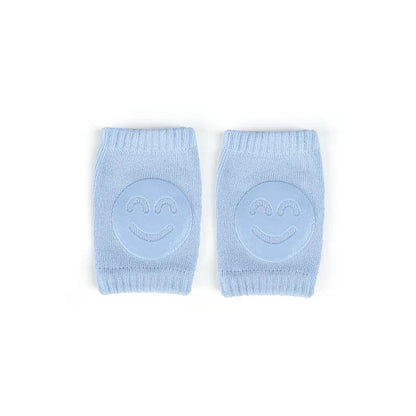 Non-slip baby knee pad in pink cotton with smiley face design, stacked with colorful pads for toddler protection during crawling.