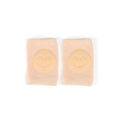 Non-slip baby knee pad in pink cotton with smiley face design, stacked with colorful pads for toddler protection during crawling.